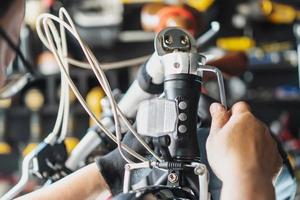 técnico hace ajustes a manillar vástago en un plegable bicicleta trabajando en taller , bicicleta reparar y mantenimiento concepto foto