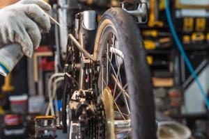 mecánico reparando bicicleta, cadena lubricante rociar para plegable bicicleta trabajando en taller , bicicleta reparar y mantenimiento concepto foto