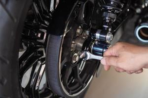 motorcycle mechanic use a wrench Adjust the belt pulley tension and drive belt on motorcycle working in garage .maintenance and repair motorcycle concept .selective focus photo