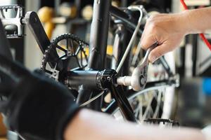 técnico hace ajustes a bielas en un plegable bicicleta trabajando en taller , bicicleta reparar y mantenimiento concepto foto