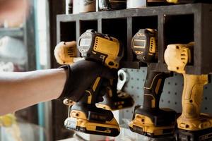 Motorcycle mechanic reaching for electric screwdriver or electric drill or impact tool on the wall to repair Motorcycle or car in garage.motorcycle maintenance and repair concept . selective focus photo