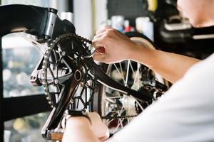 técnico hace ajustes a bielas y reparando el palanca de cambios en un plegable bicicleta trabajando en taller , bicicleta reparar y mantenimiento concepto foto