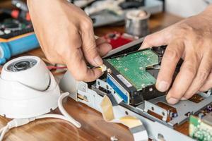 Technician remove a hard disk drive from the CCTV DVR recorder case, to install a new hard drive and upgrading to a Solid State for backup CCTV camera , electrical work and cctv concept photo