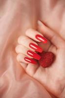 Girl's hands with red manicure and decoratine heart photo