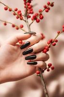 manos de una joven con manicura negra en las uñas foto