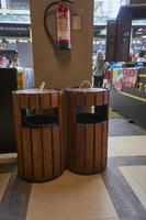 A garbage collection cans with hanged fire extinguisher in the corner of building. Rubbish bin, garbage and waste bin made of wooden material. Clean and protected. Decorating inspiration. photo