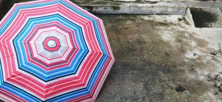 vistoso estampado paraguas en el yarda después lluvia. arco iris sombrilla. natural antecedentes. vistoso paraguas, símbolo de lluvioso clima estación. Copiar espacio. bandera foto