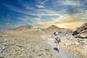 un mujer caminante en un alto montaña sendero foto