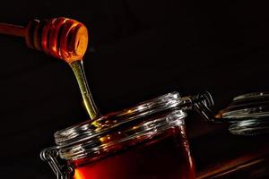 Glass jar with honey and the natural wooden stick photo