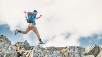 deportivo hombre saltos Entre rocas en el montañas foto