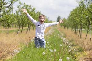 Happy boy rejoices in the spring garden. School summer holidays have begun. photo