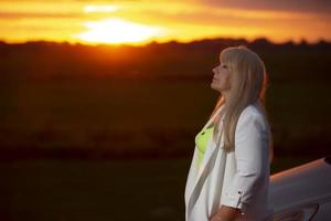 Beautiful middle age blond woman against sunset sky. photo