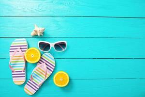 Flip flops, sunglasses and oranges on blue wooden background. Top view and copy space