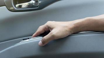 Passenger's hand holds armrests beside the door of car from the inside. Driver finger pulls the windowpane button. photo