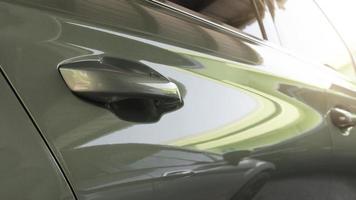 Beautiful car door opener handle. On the glossy green car floor. Blurred view of sunlight shining in front. photo