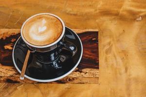 A cup of hot cappuccino with foam art on the surface serve on the wooden table. photo