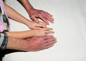 The hands of an old man and a child, holding each other. photo