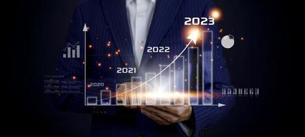 Business growth data chart arrow with diagram 2023 budget, Businessman pointing arrow graph corporate future growth year 2022 to 2023, Development to success and motivation. photo