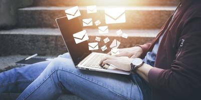 Man working outdoor using laptop with communication icons, letter icon, email icons, and newsletter email and protect your personal information or spam mail, Customer service call center contact. photo