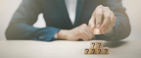 Hand hold Wooden cube block in question mark mean what on cement table background, column of wooden blocks with question sign mark. copy space,FAQ frequently asked questions, Answer, Information photo