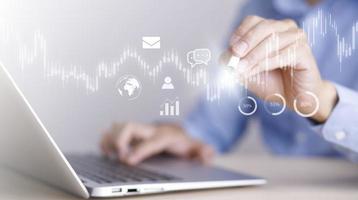 businessman hand type on the laptop of company profit with colleagues partner explain with virtual dashboard statistic chart stock infographic, graphs, cryptocurrency, and new trading platforms photo