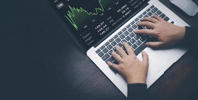 Woman using laptop with planning and strategy, Stock market, Business growth down, Concept of financial crisis, echnical price graph and indicator, red candlestick chart with analyzing forex trading. photo