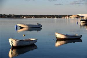 Tres pequeño barco en el apuntalar a puesta de sol foto