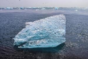 playa de diamantes en islandia con icebergs azules derritiéndose sobre arena negra y hielo brillando con la luz del sol. foto