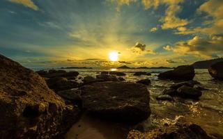 vistoso puesta de sol cielo terminado Oceano con rocas foto