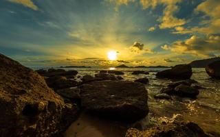 Colorful sunset sky over ocean with rocks photo