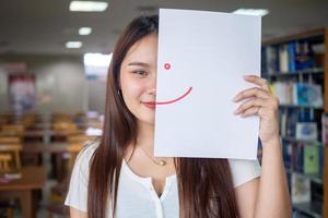 retrato de gracioso emocional niña felicidad, positivo emociones contento y sonriente niña con un sonrisa pintado en papel. foto
