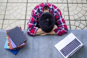 chico estudiante cansado desde estudiando sentar y descanso en el colegio escritorio. foto