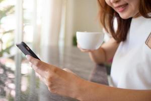 Women sit and drink coffee in the living room at home. enjoying shopping online with smartphone, concept of shopping through application online shopping photo