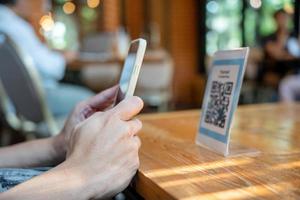 woman use smartphone to scan QR code to pay in cafe restaurant with a digital payment without cash. Choose menu and order accumulate discount. E wallet, technology, pay online, credit card, bank app. photo