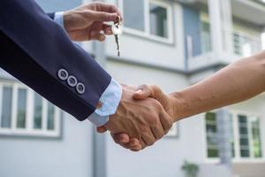 Agent sells the house shake hand with the buyer and send house key to the buyer. photo