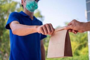 Delivery man in blue uniform service send food to customers orders online from home. delivery, express delivery, food delivery and online shopping concepts photo