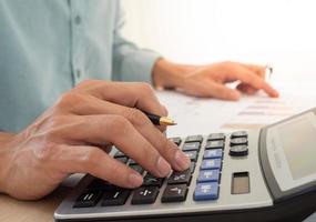 A business man using a calculator to calculate expenses from receipts placed on the table. debt concept photo