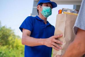 The deliveryman carries a food bag and wears a mask, ready to deliver food online as per the customer's order for quick home delivery and free shipping. Online shopping and express delivery photo