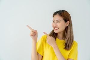 Portrait asian beautiful girl pointing blank space isolated background. Happy woman pointing on something. young female standing pointing finger sideways, billboard, introduction, advertisement, space photo