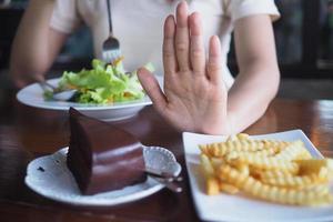 uno mujer es controlador peso. pastel y francés papas fritas fuera y escoger a comer vegetal tallas foto