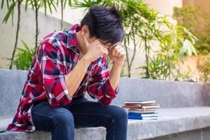 asiático masculino estudiantes sentado preocupado estresado, acerca de el ha fallado examen resultados. foto