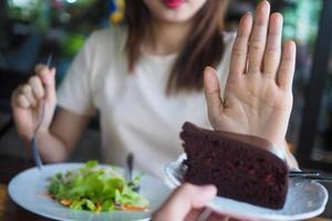 una de las chicas de salud usó una mano para empujar un plato de pastel de chocolate. negarse a comer alimentos que contengan grasas trans. foto