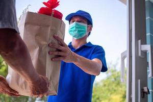 The deliveryman carries a food bag and wears a mask, ready to deliver food online as per the customer's order for quick home delivery and free shipping. Online shopping and express delivery photo