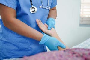 médico tomados de la mano paciente anciana asiática, ayuda y atención en el hospital. foto