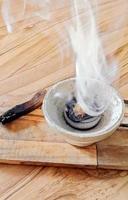 A dense smoke can be seen emanating from a bowl-shaped table holding fragrant incense. photo