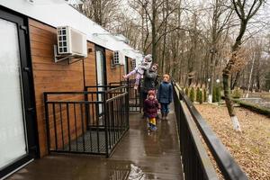 Father with three kids on terrace of one-storey modular houses in spring rainy forest. photo