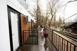 Kids walking on terrace of one-storey modular houses in spring rainy forest. photo