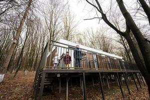 Kids walking on terrace of one-storey modular houses in spring rainy forest. photo