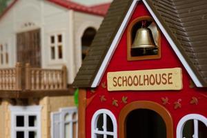 Red school house with bell plastic toy. photo