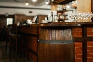 Empty bar with old barrel interior,  wooden furniture and pub counter without bartenders. photo